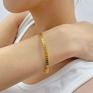 Close-up of golden geometric block bracelet with modern 18K gold polished finish on wrist