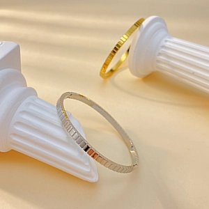 Detailed view of gold and silver bangle bracelets with modern geometric cube texture