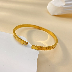 Close-up of gold geometric bangle with modular square segments and side clasp