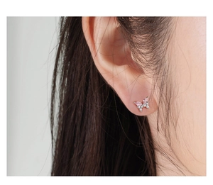 Macro detail of silver butterfly earring with pink marquise stones on ear lobe