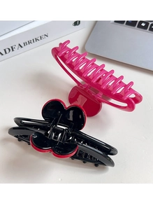 Detail of large candy color hair claws and red heart clip on desk setup