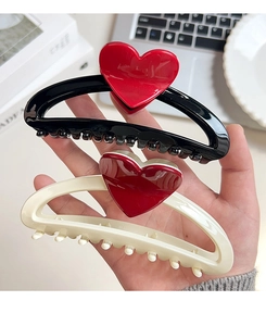 Close-up of two large 13cm heart-shaped hair claw clips in red, black, and cream colors