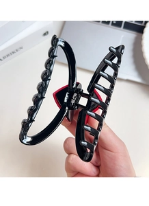 Macro view of a 13cm black resin hair claw with a red heart and metal spring