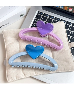 Close-up of large pastel heart claw clips on a linen cloth with home office background