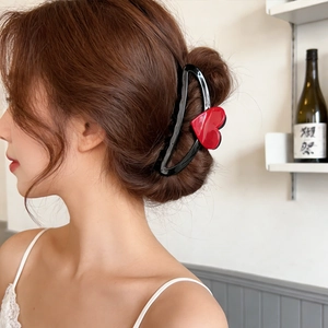 Large black hair claw clip with a red heart, worn in a stylish updo on a female model