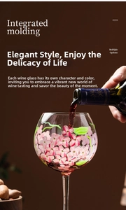 Action shot of red wine pouring into a hand-painted floral wine glass with pink petals
