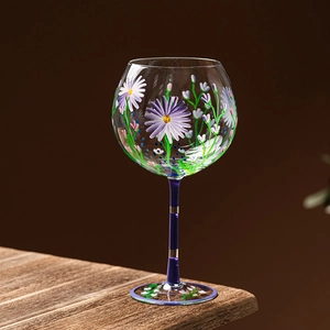 Hand-painted floral balloon wine glass with purple daisies on a dark blue stem base