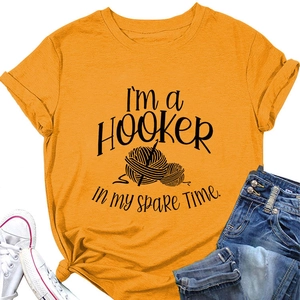 Flat lay of an orange graphic t-shirt with crochet theme, paired with jeans and sneakers