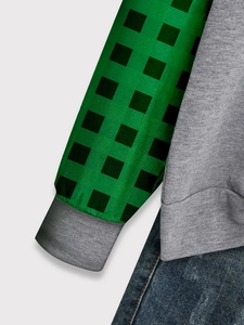 Détail du sweat à manches longues avec manches à carreaux verts et tissu en maille grise