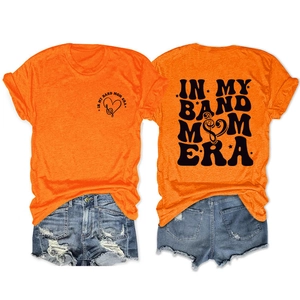 Détails de l'imprimé graphique In My Band Mom Era sur le devant et l'arrière du t-shirt orange