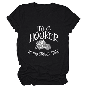 Flat lay of a black cotton T-shirt featuring a white 'I'm a Hooker' crochet theme print