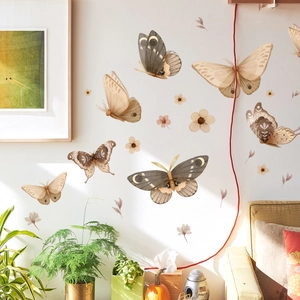 Detalle de vinilos decorativos de polillas bohemias en pared blanca de salón acogedor