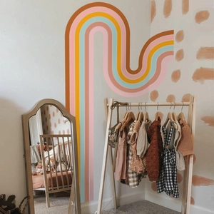 Bohemian large rainbow wall sticker in a cozy nursery room with a wooden clothes rack