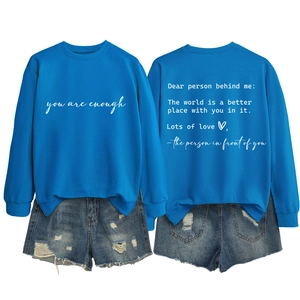 Detail of blue crewneck sweatshirt with 'you are enough' text and ripped denim shorts