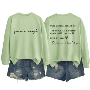 Detail of mint green sweatshirt with healing text and ripped denim shorts set