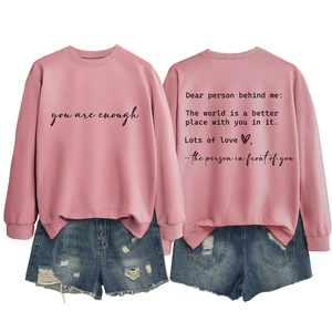 Close-up of pink crewneck sweatshirt with 'you are enough' print and ripped denim shorts
