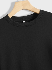 Close-up of black sweatshirt ribbed collar and size M tag on a wooden hanger