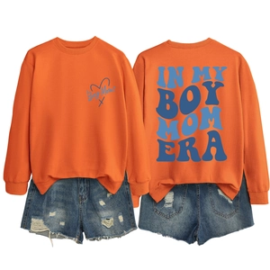 Flat lay of an orange Boy Mom sweatshirt featuring retro back print and ribbed neck detail