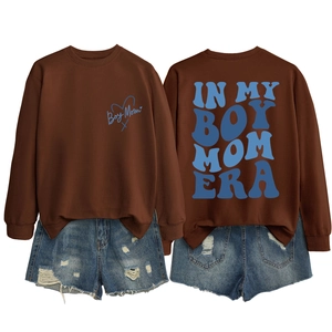 Detailed view of brown crewneck sweatshirt with Boy Mom Era back print and denim shorts