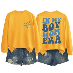 Flat lay of yellow long sleeve sweatshirt with In My Boy Mom Era print and denim shorts