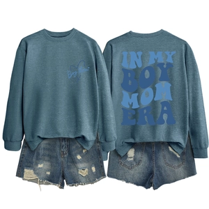 Detail view showing printed Boy Mom Era graphics on crewneck sweatshirt and denim shorts