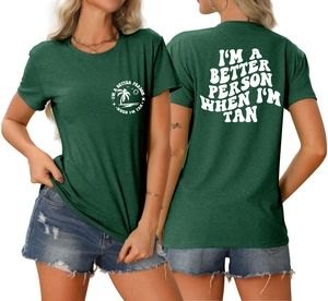 Détail du t-shirt vert foncé avec palmier et texte I'M A BETTER PERSON WHEN I'M TAN