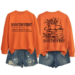 Flat lay of an orange crewneck sweatshirt with Booktrovert print and denim shorts