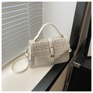 Detail of white tweed and leather handbag with gold buckle and curved handle