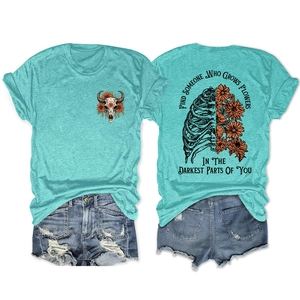 Detail of turquoise T-shirt back print featuring ribcage with orange flowers and text