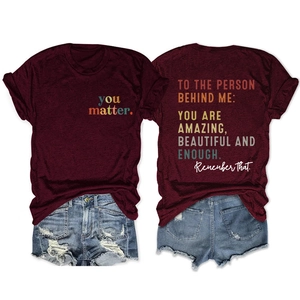 Detail of burgundy T-shirt with 'TO THE PERSON BEHIND ME' quote and ripped denim shorts