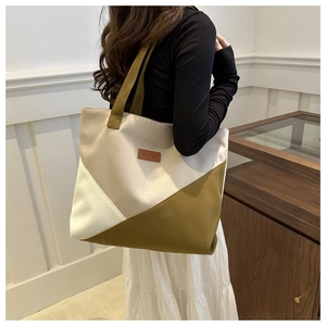 Detail of color-block canvas tote bag with brown leather FASHION label and long handles