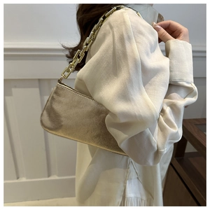 Detailed close-up of a trendy gold baguette bag with a chunky metallic chain strap