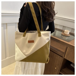 Detail of color-block canvas tote bag with fashion tag and geometric patchwork texture