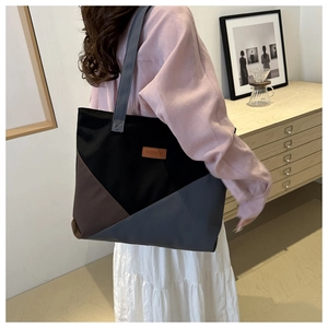 Detailed view of a spacious color-block tote bag worn in a cozy indoor lifestyle setting
