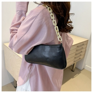Dettaglio di una borsa sottobraccio in pelle nera con tracolla a catena dorata e finitura