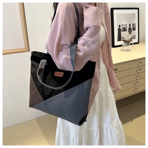 Detail of color-block canvas tote bag with brown leather label and wide straps