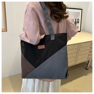 Detail of color-block canvas tote bag featuring Fashion leather tag and woven shoulder strap