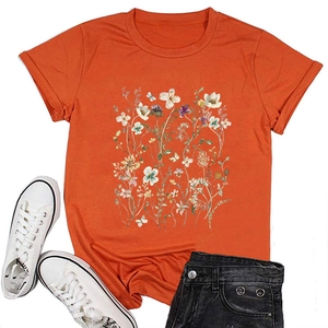 Flat lay of an orange floral t-shirt paired with denim shorts and white sneakers
