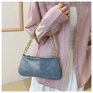 Close-up of grey felt handbag with chunky gold chain strap worn over a pink shirt