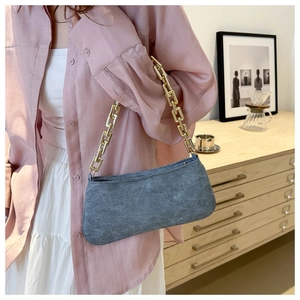 Dettaglio della borsa a spalla in denim blu scuro con catena dorata a maglie larghe