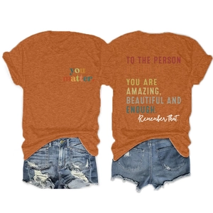 Flat lay of women's orange T-shirt with 'you matter' text and distressed denim shorts