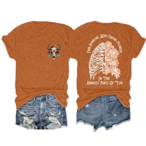 Detail of flower-adorned rib cage print and emotional quote on orange cotton T-shirt