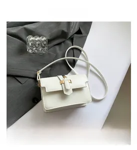 Detailed view of white leather crossbody bag with golden metal lock on a grey suit