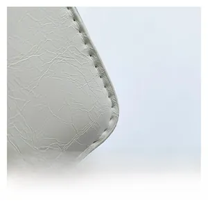 Close-up of white leather handbag corner showing fine stitching and soft pleat texture