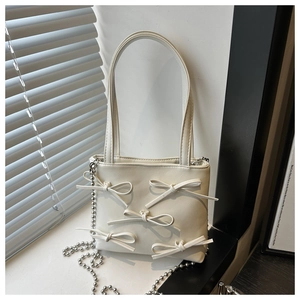 Close-up of white leather handbag with elegant bow details and silver beaded metal chain