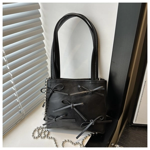 Close-up of black bow-knot handbag with matte leather texture and silver bead chain