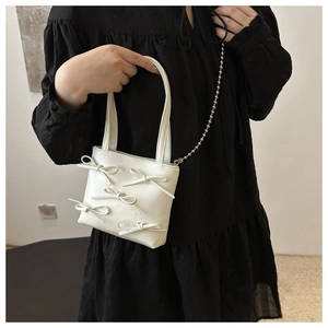 Detail of white PU leather bucket bag featuring elegant 3D bows and silver bead chain