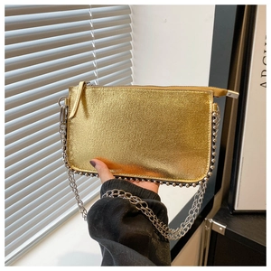 Detail of gold envelope bag featuring silver rivet trim and metal chain shoulder strap