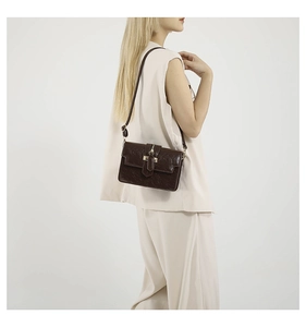 Brown vintage faux leather crossbody bag with gold buckle shown on shoulder of a model