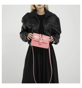 Pink glossy rectangular crossbody bag worn by a model in a black leather jacket